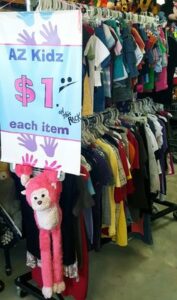 One dollar rack with plush monkey holding up sign.